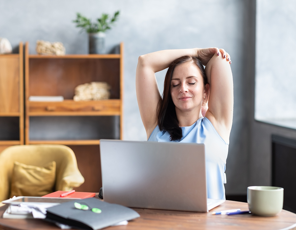 Business woman stretches her body doing yoga exercise at coffee break.